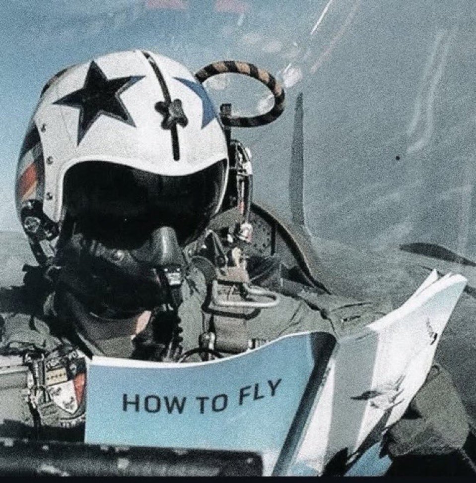 Fighter pilot mid-flight reading a manual titled How to Fly
